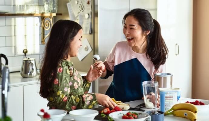 Vrouw en kind lachen terwijl ze eten klaarmaken