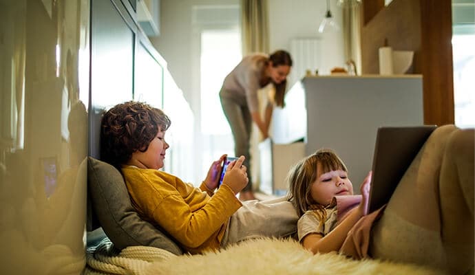 Kinderen gebruiken tablets met moeder op de achtergrond