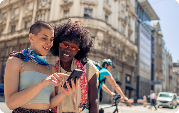 Twee lachende vrouwen die samen naar een telefoon kijken