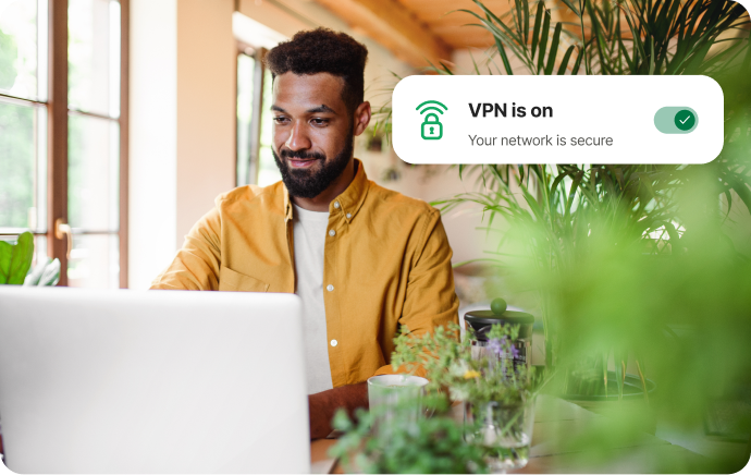 Man omringd door planten die lachend naar een laptop kijkt